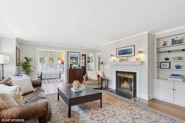 311 Wagner Rd, Northfield, IL 60093 - living room featuring wood finished floors, a glass covered fireplace, ornamental molding, built in features, and radiator