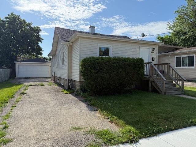 1023 N Elmwood Ave, Waukegan, IL 60085 - bungalow-style house featuring a chimney, a garage, an outbuilding, and a front yard