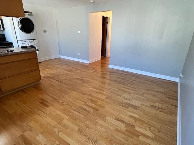 5209 S Leclaire Ave Unit 3B, Chicago, IL 60638 - unfurnished living room with estacked washer and dryer and light wood-style floors