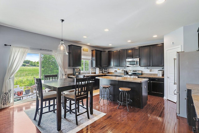 3512 Chancery Ln, Carpentersville, IL 60110 - kitchen with appliances with stainless steel finishes, a kitchen island, dark wood-style flooring, a breakfast bar, and recessed lighting
