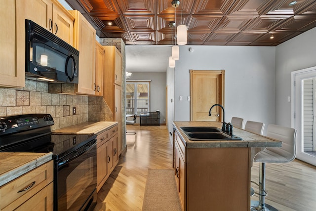 206 W N St, Leroy, IL 61752 - kitchen featuring black appliances, an ornate ceiling, tasteful backsplash, light wood-type flooring, and an island with sink