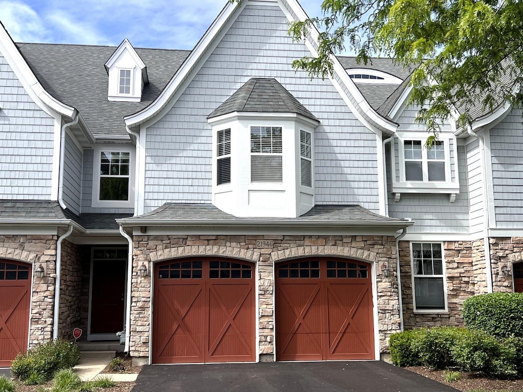 21946 W Tori Ln, Deer Park, IL 60010 - view of front facade with an attached garage, stone siding, asphalt driveway, and roof with shingles