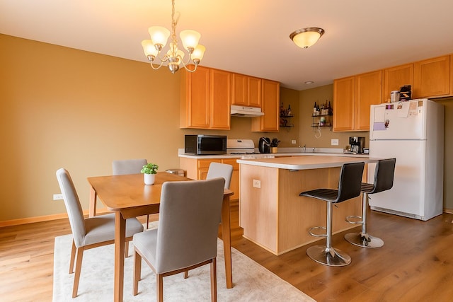 1077 Marcello Dr, Hampshire, IL 60140 - kitchen featuring freestanding refrigerator, under cabinet range hood, stainless steel microwave, light wood-type flooring, and a center island