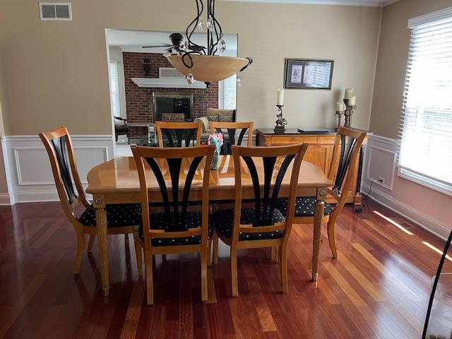 1312 Frederick Ln, Naperville, IL 60565 - dining area featuring a fireplace, plenty of natural light, a decorative wall, wainscoting, and dark wood-style floors