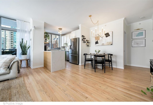 600 N Dearborn St Unit 701, Chicago, IL 60654 - kitchen with stainless steel appliances, a chandelier, light wood-style flooring, crown molding, and white cabinets