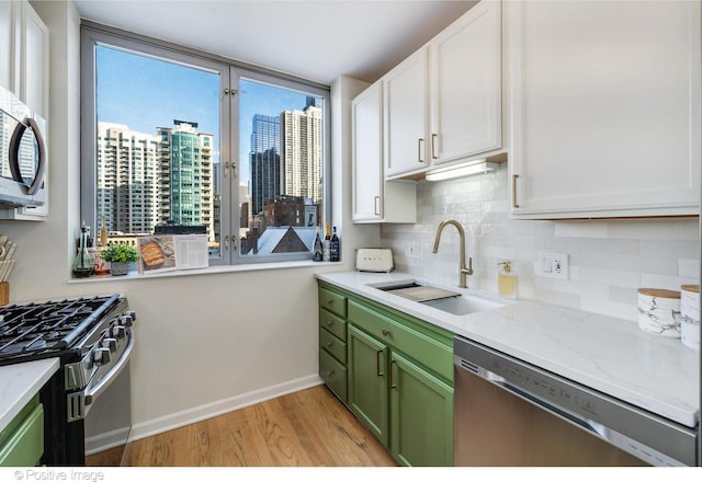 600 N Dearborn St Unit 701, Chicago, IL 60654 - kitchen with stainless steel appliances, green cabinetry, light wood-type flooring, backsplash, and white cabinetry