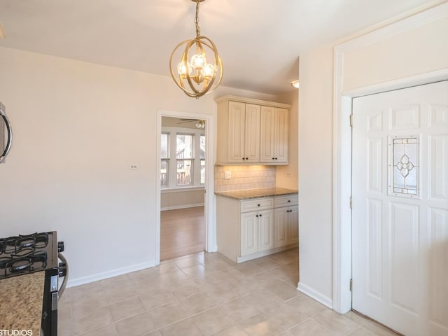 2614 W Lunt Ave, Chicago, IL 60645 - kitchen featuring a chandelier, cream cabinets, decorative backsplash, range with gas cooktop, and light stone counters