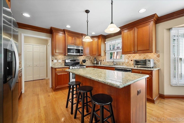 1200 Crestview Dr, Batavia, IL 60510 - kitchen featuring appliances with stainless steel finishes, light wood-style flooring, a kitchen breakfast bar, brown cabinets, and crown molding