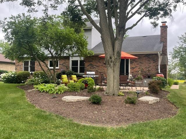 10S305 Havens Dr, Downers Grove, IL 60516 - view of front of house with a chimney, brick siding, a front lawn, and a patio area
