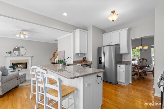 39W183 E Burnham Ln, Geneva, IL 60134 - kitchen with stainless steel fridge, a peninsula, light wood-style flooring, a breakfast bar area, and white cabinetry