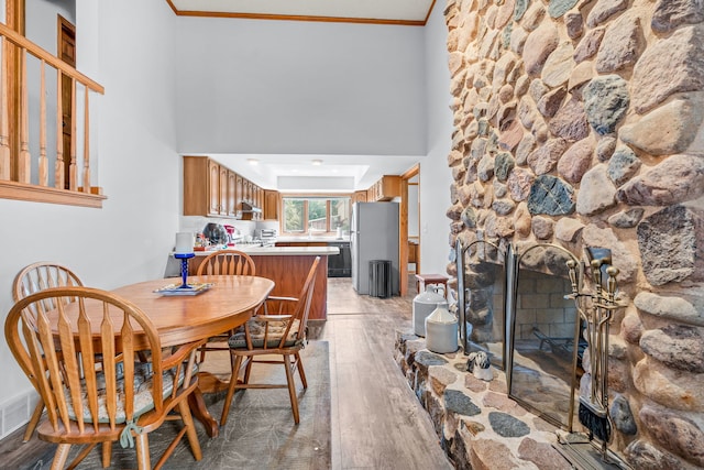 35W186 Duchesne Dr, Dundee, IL 60118 - dining space featuring light wood-style floors, a fireplace, crown molding, and a towering ceiling