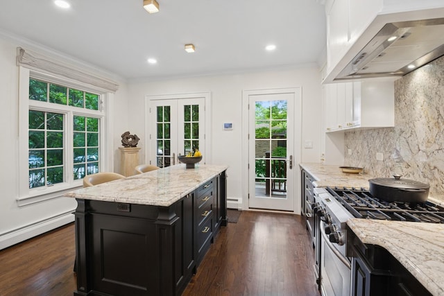 3045 W Ardmore Ave, Chicago, IL 60659 - kitchen featuring wall chimney range hood, stainless steel range with gas cooktop, dark cabinets, white cabinets, and backsplash