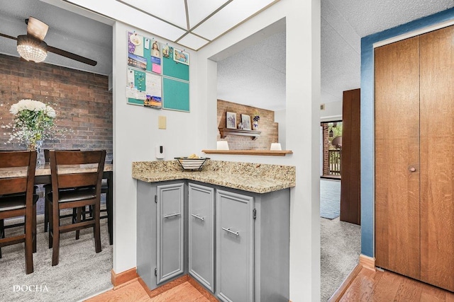 1423 Woodbridge Rd Unit 2C, Joliet, IL 60436 - kitchen featuring gray cabinetry, light wood-style flooring, light stone countertops, and light carpet