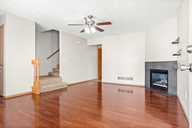 23 Fetzer Dr Unit 3, Bloomington, IL 61704 - unfurnished living room with ceiling fan, wood finished floors, stairway, a tile fireplace, and a textured ceiling