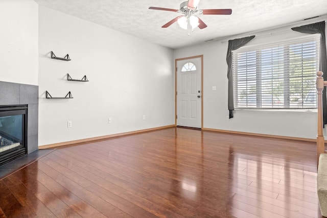 23 Fetzer Dr Unit 3, Bloomington, IL 61704 - unfurnished living room featuring ceiling fan, a textured ceiling, a tiled fireplace, and wood finished floors
