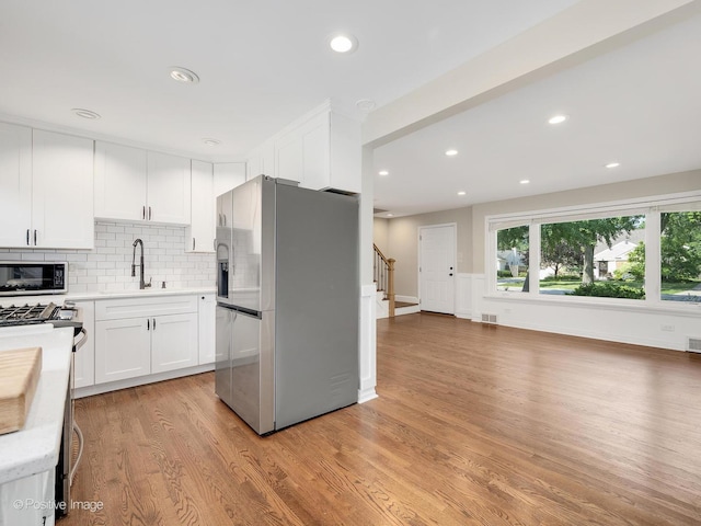 19 Indian Dr, Clarendon Hills, IL 60514 - kitchen with stainless steel appliances, light wood-type flooring, white cabinets, light countertops, and tasteful backsplash