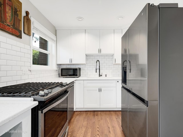 19 Indian Dr, Clarendon Hills, IL 60514 - kitchen featuring appliances with stainless steel finishes, light wood finished floors, decorative backsplash, white cabinets, and recessed lighting