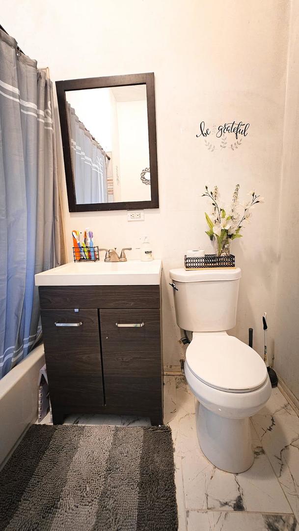 7250 S Morgan St, Chicago, IL 60621 - full bathroom with marble look tile flooring, vanity, and shower / bath combo with shower curtain