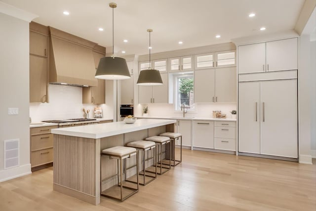 1437 Ashland Ave, River Forest, IL 60305 - kitchen with custom exhaust hood, a center island, light countertops, decorative backsplash, and light wood-style flooring
