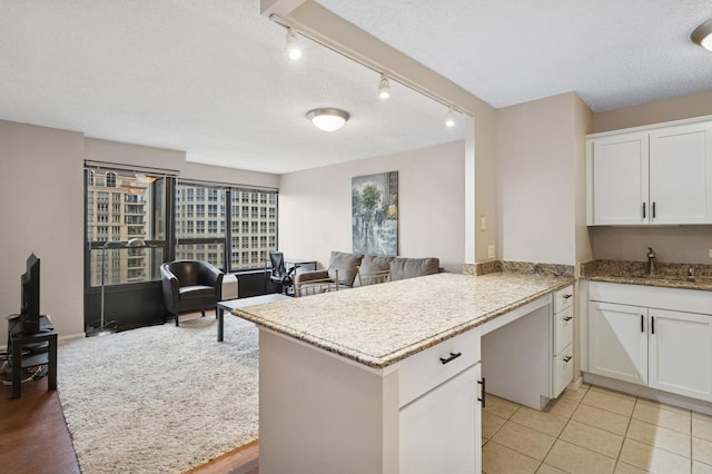 30 E Huron St Unit 2108, Chicago, IL 60611 - kitchen with white cabinets, light stone countertops, track lighting, open floor plan, and a peninsula