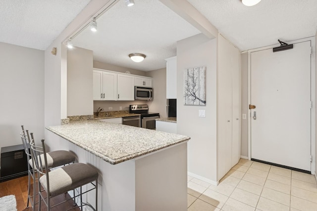30 E Huron St Unit 2108, Chicago, IL 60611 - kitchen featuring stainless steel appliances, a breakfast bar, white cabinetry, a textured ceiling, and a peninsula