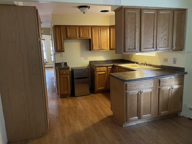2020 W 53rd Pl, Chicago, IL 60609 - kitchen featuring light wood-style flooring, a peninsula, dark countertops, freestanding refrigerator, and brown cabinets