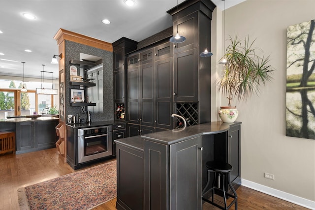 849 W Monroe St Unit Ph5, Chicago, IL 60607 - kitchen featuring oven, dark countertops, a peninsula, dark wood-style flooring, and a breakfast bar