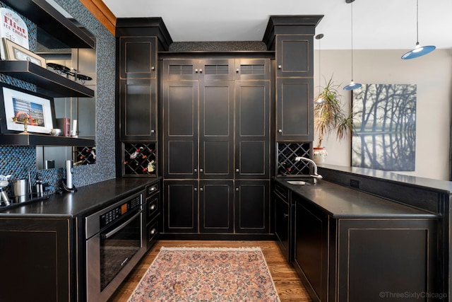 849 W Monroe St Unit Ph5, Chicago, IL 60607 - kitchen with wall oven, dark countertops, tasteful backsplash, wood finished floors, and dark cabinetry