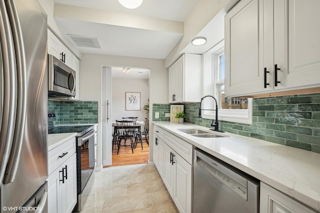 840 Forest Ave Unit C, Evanston, IL 60202 - kitchen featuring appliances with stainless steel finishes, decorative backsplash, white cabinets, and light stone countertops