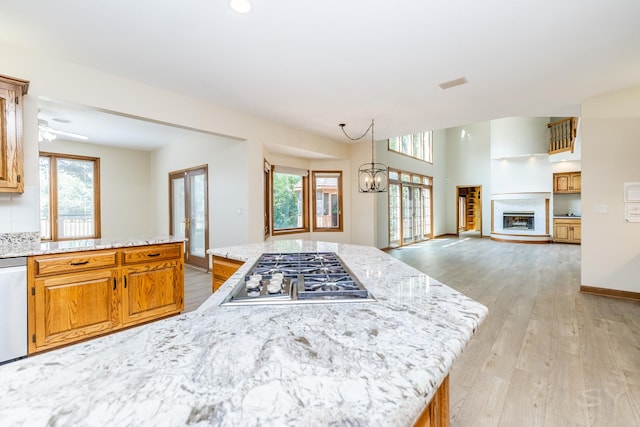 771 E Hickory Ave, Addison, IL 60101 - kitchen with stainless steel gas stovetop, light wood-style flooring, light stone countertops, a fireplace, and brown cabinets