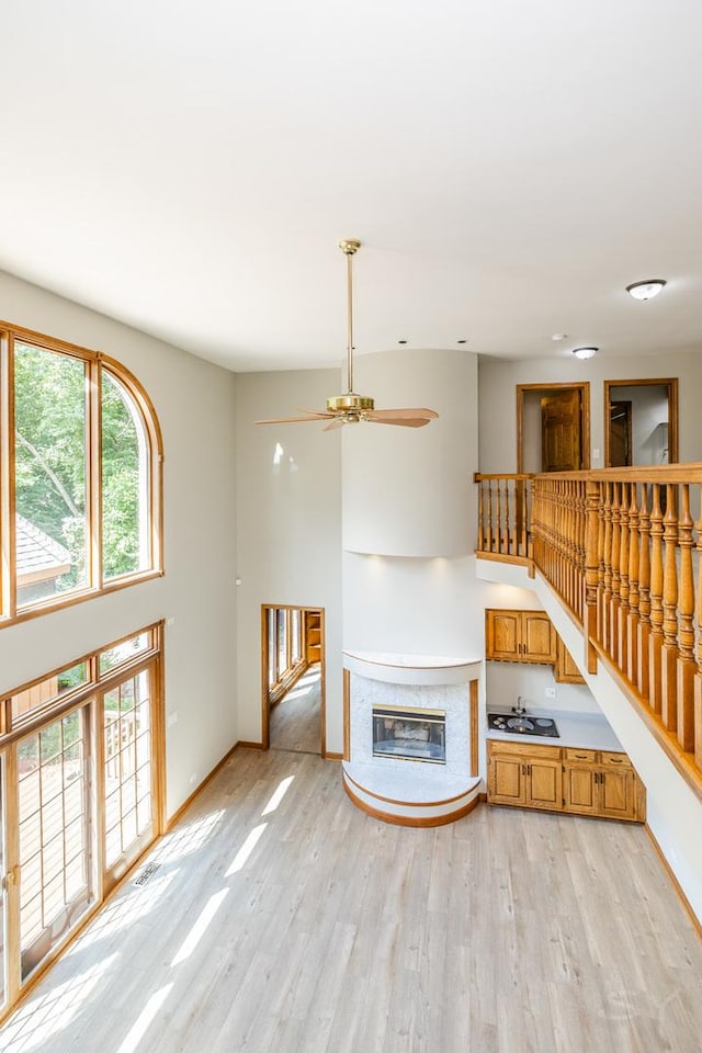 771 E Hickory Ave, Addison, IL 60101 - unfurnished living room featuring light wood-type flooring, a ceiling fan, and a glass covered fireplace