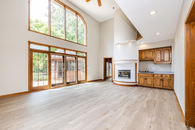 771 E Hickory Ave, Addison, IL 60101 - unfurnished living room featuring a towering ceiling, light wood finished floors, a glass covered fireplace, a ceiling fan, and recessed lighting