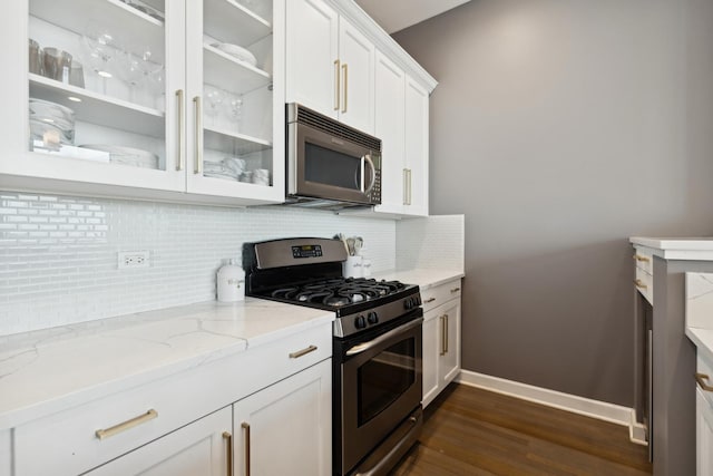 500 W Superior St Unit 1504, Chicago, IL 60654 - kitchen featuring appliances with stainless steel finishes, dark wood finished floors, glass insert cabinets, backsplash, and light stone counters