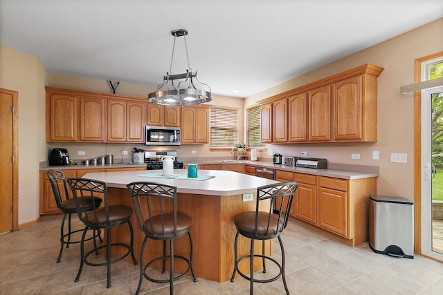 244 Prescott Ave, Elgin, IL 60124 - kitchen with stainless steel appliances, a center island, a kitchen breakfast bar, light countertops, and light tile patterned flooring
