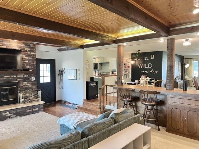 1413 Eustace Dr, Dixon, IL 61021 - living area with a wooden ceiling with exposed beams, ornate columns, and a brick fireplace
