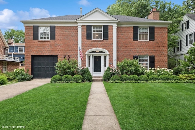 2735 Simpson St, Evanston, IL 60201 - greek revival house featuring an attached garage, a front yard, a chimney, driveway, and brick siding