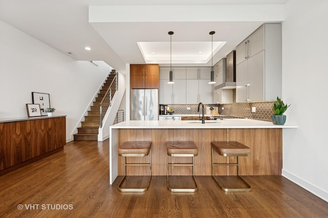 2125 N Mozart St Unit 3, Chicago, IL 60647 - kitchen with stainless steel refrigerator, wall chimney range hood, a raised ceiling, a peninsula, and decorative backsplash