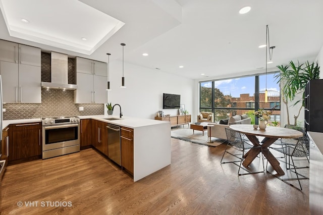 2125 N Mozart St Unit 3, Chicago, IL 60647 - kitchen featuring wall chimney range hood, appliances with stainless steel finishes, expansive windows, a peninsula, and tasteful backsplash