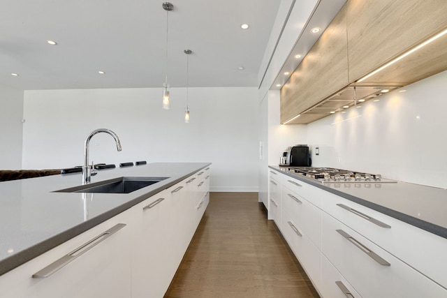 2413 W Fullerton Ave Unit 3, Chicago, IL 60647 - kitchen with modern cabinets, stainless steel gas stovetop, white cabinetry, hanging light fixtures, and dark wood-type flooring