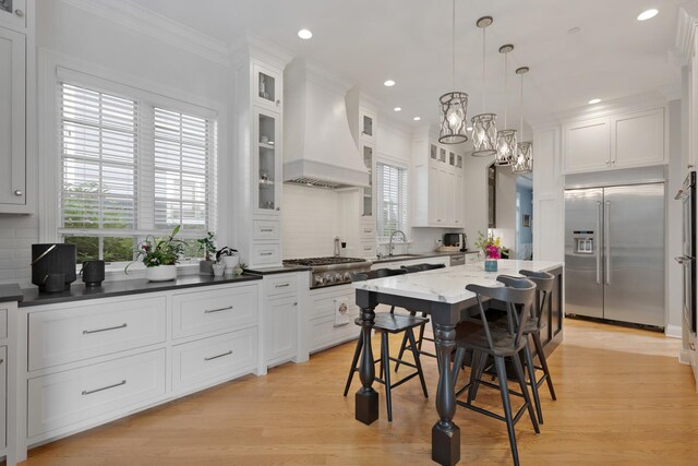 700 E Sunnyside Ave, Libertyville, IL 60048 - kitchen with stainless steel appliances, custom range hood, white cabinets, backsplash, and a breakfast bar area