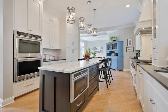 700 E Sunnyside Ave, Libertyville, IL 60048 - kitchen with stainless steel appliances, custom exhaust hood, white cabinetry, hanging light fixtures, and crown molding