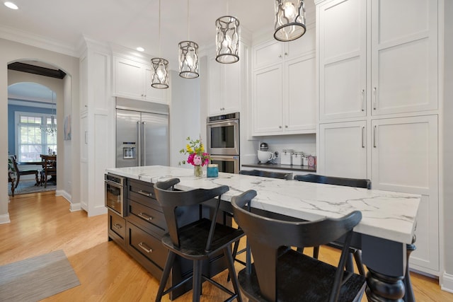 700 E Sunnyside Ave, Libertyville, IL 60048 - kitchen featuring stainless steel appliances, white cabinetry, recessed lighting, arched walkways, and a center island