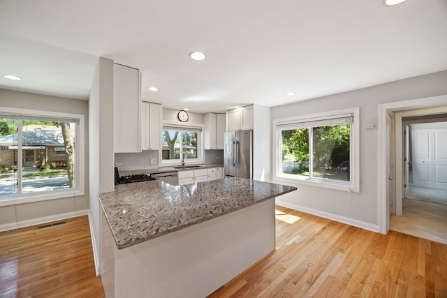 6037 N Nagle Ave, Chicago, IL 60646 - kitchen featuring stainless steel appliances, light stone countertops, light wood finished floors, white cabinets, and recessed lighting