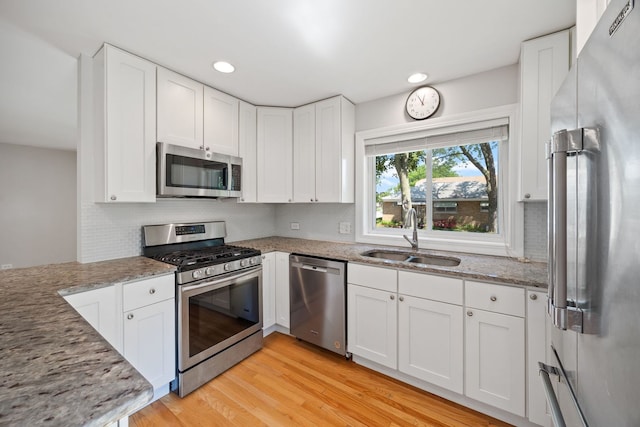 6037 N Nagle Ave, Chicago, IL 60646 - kitchen featuring appliances with stainless steel finishes, light stone countertops, white cabinets, light wood-type flooring, and backsplash