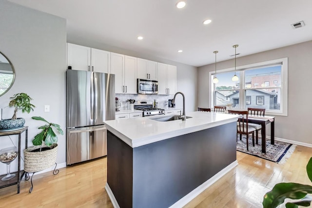 1601 N Paulina St Unit 2D, Chicago, IL 60622 - kitchen featuring stainless steel appliances, light wood-style flooring, white cabinets, backsplash, and light countertops
