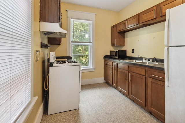809 W 4th St, Sterling, IL 61081 - kitchen featuring white appliances, range hood, dark countertops, and brown cabinets