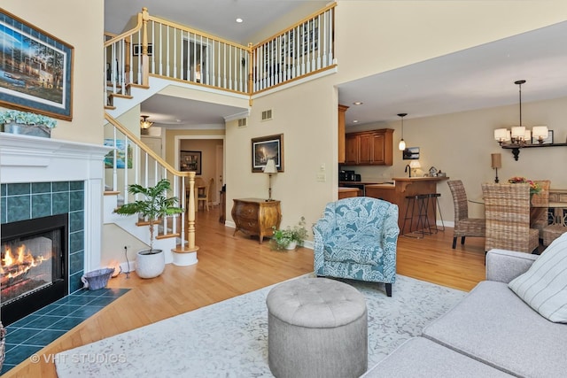 3716 King Charles Ln, Saint Charles, IL 60174 - living area featuring light wood-type flooring, stairs, a fireplace, a towering ceiling, and a chandelier