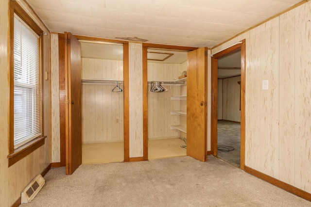 607 W Grant Ave, Pontiac, IL 61764 - unfurnished bedroom featuring wooden walls, multiple closets, and carpet floors