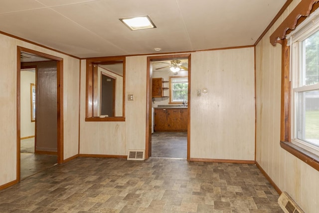 607 W Grant Ave, Pontiac, IL 61764 - spare room with stone finish flooring, a ceiling fan, healthy amount of natural light, and wooden walls