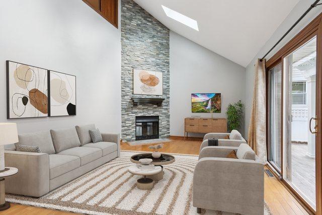 584 Beaconsfield Ave, Naperville, IL 60565 - living room with light wood finished floors, high vaulted ceiling, a skylight, and a large fireplace